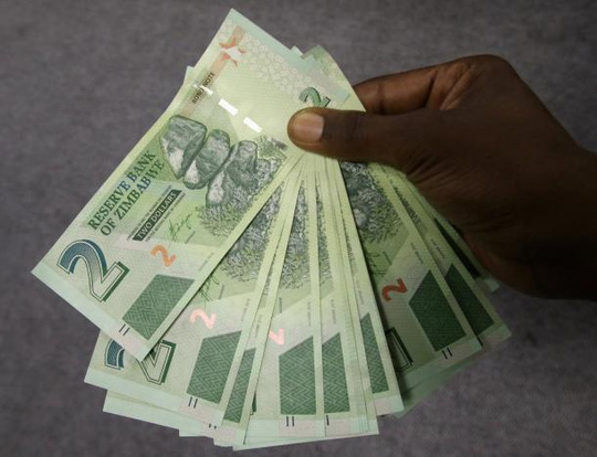Một người đàn ông Zimbabwe với số tiền trái phiếu rút được hôm 28-11 ở thủ đô Harare. Ảnh: REUTERS