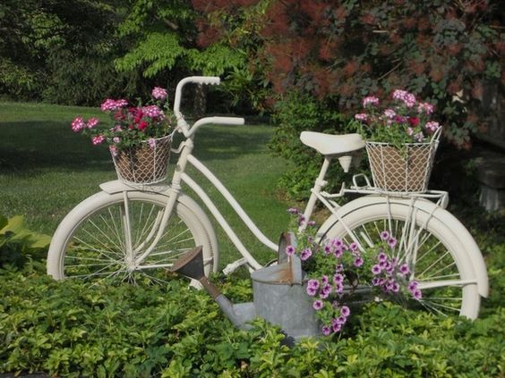 Chiếc xe đạp trắng nổi bật trên nền xanh cây cỏ trong vườn.