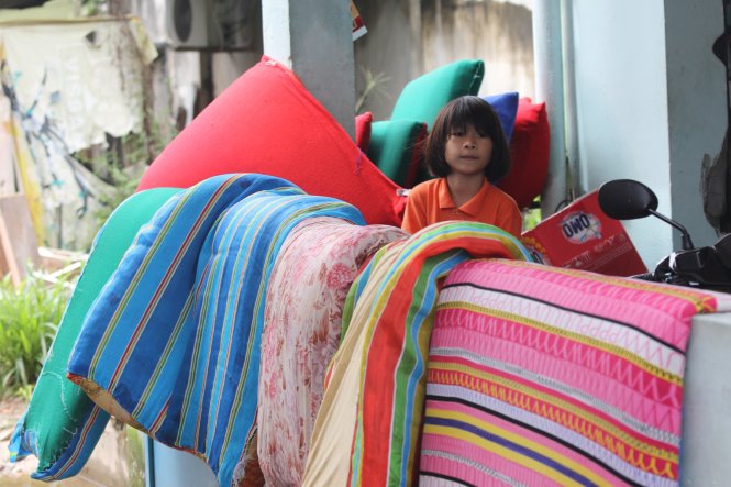 Một em bé mang chăn gối, nệm ra ngoài phơi tại đường số 52 (P.Hiệp Bình Chánh, Q.Thủ Đức) do nước tràn vào nhà gây ướt - Ảnh: MINH PHƯỢNG