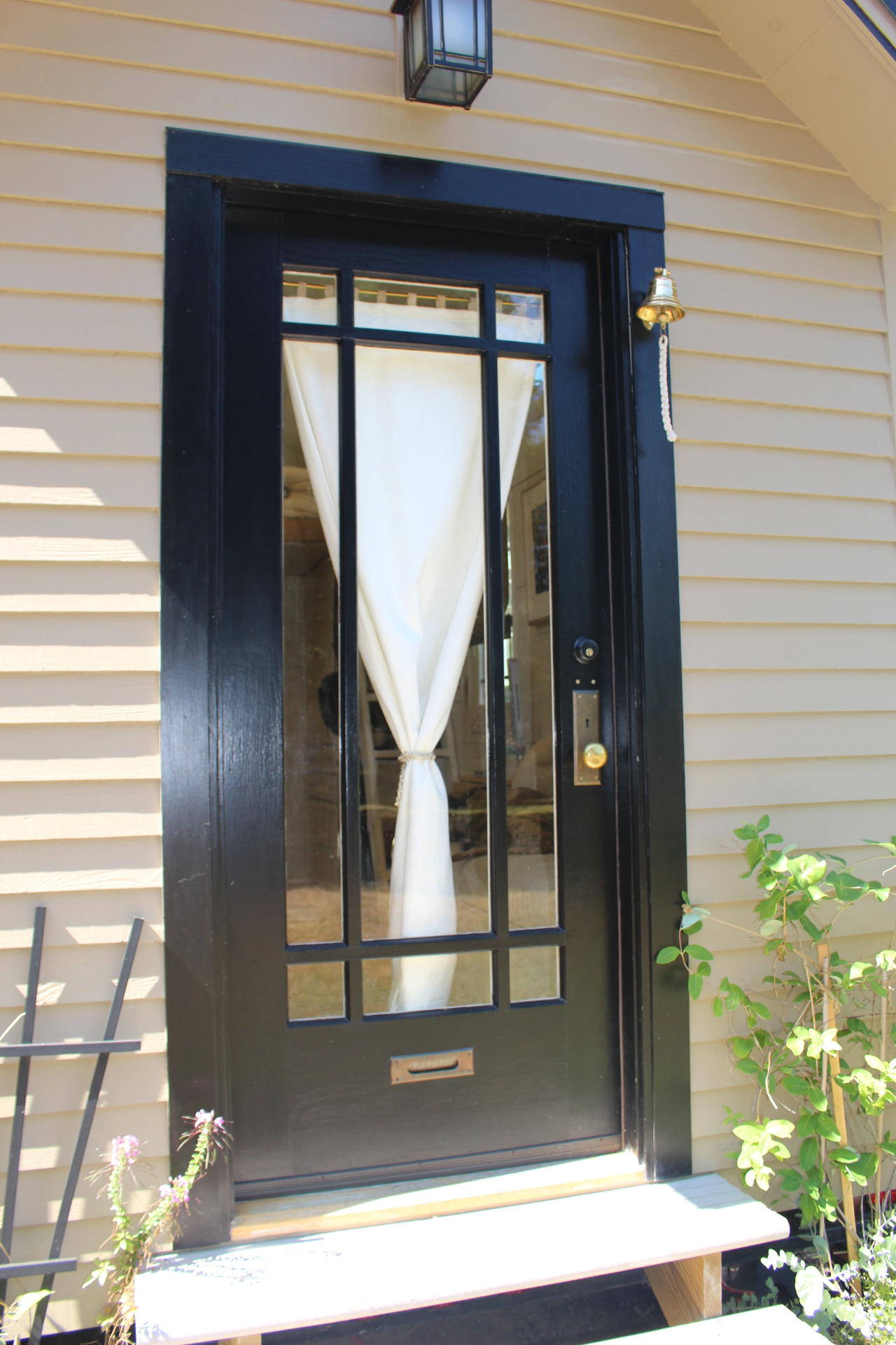 Lối vào được chủ nhà chăm chút với những chậu hoa nhỏ đầy màu sắc trước thềm. Bên trong cửa chính là tấm rèm trắng tạo nét duyên dáng cho ngôi nhà.