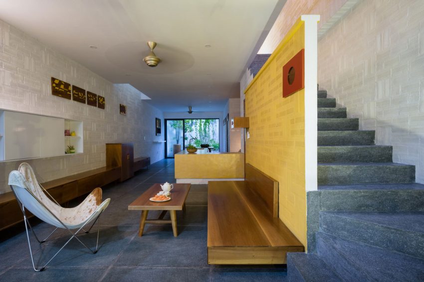 Phòng khách được bài trí với bô bàn ghế gỗ đơn giản cùng bức tường vàng làm sáng bừng cả ngôi nhà.