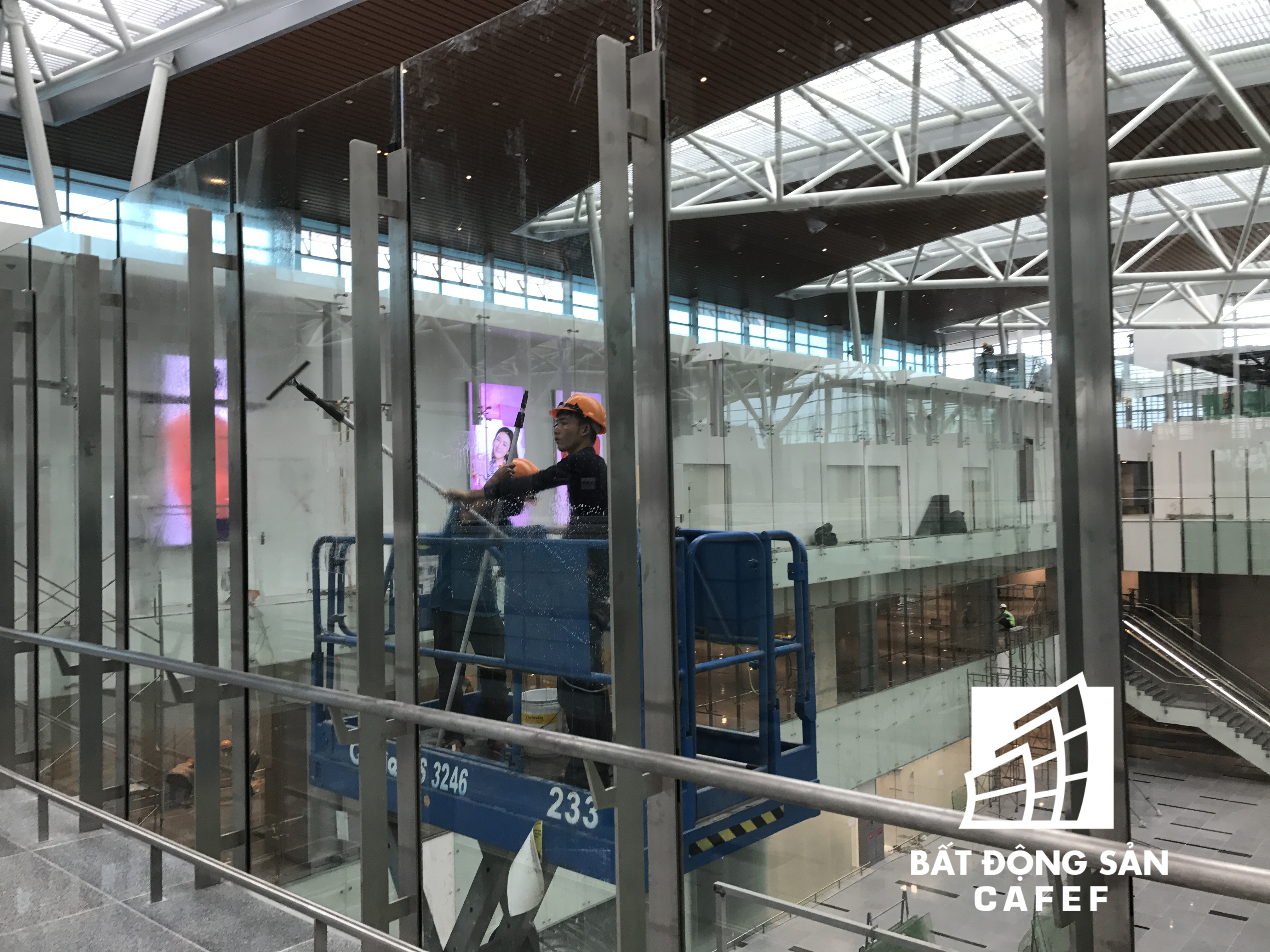 Đội ngũ công nhân đang lau chùi toàn bộ hệ thống kính tường bên trong nhà ga.