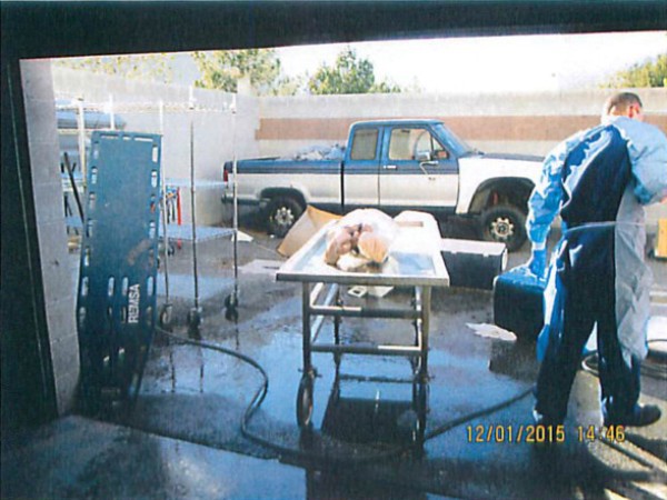 Người đàn ông trong trang phục bảo hộ y tế đang cầm vòi xịt nước nhằm mục đích rã đông xác chết.
