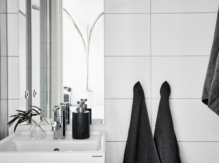 Khu vực vệ sinh sáng bóng với gạch ốp tường trắng cao sát trần.