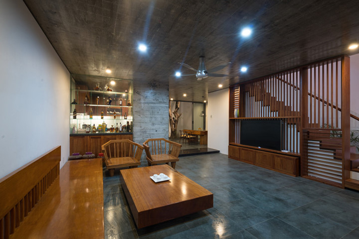 Công trình nằm trong vùng đất thấp, bị ngập lụt về mùa mưa nên nền tầng một được đẩy lên cao so với mặt đường. Không gian phòng khách tuyệt đẹp với bộ bàn ghế gỗ bóng loáng.