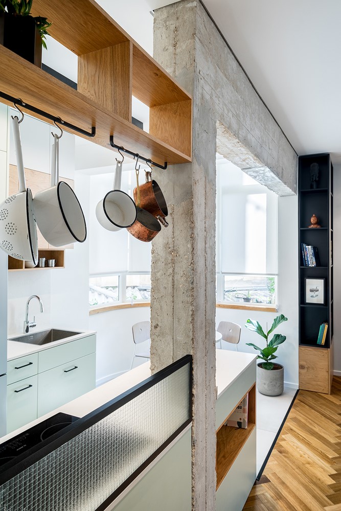 Căn bếp với tông màu trắng tách mình ra khỏi không gian phòng khách. Nhiều chi tiết cột kèo được giữ nguyên vẻ ngoài thô ráp theo ý của chủ đầu tư.