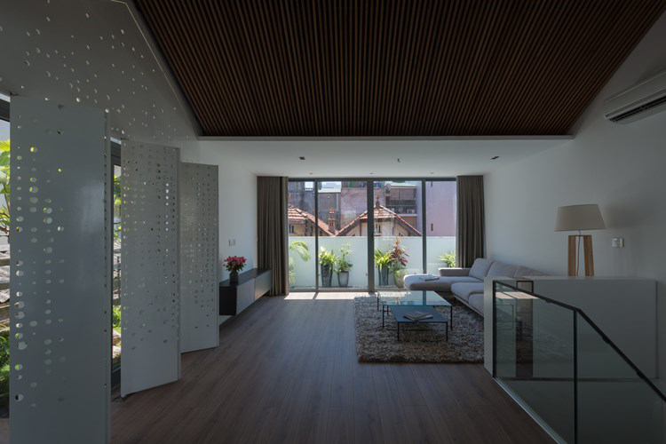 Không gian phòng khách vô cùng thoáng mát và rộng rãi với hoa nắng nhảy nhót nhờ hệ thống cửa gấp với rất nhiều những lỗ hổng hình tròn.