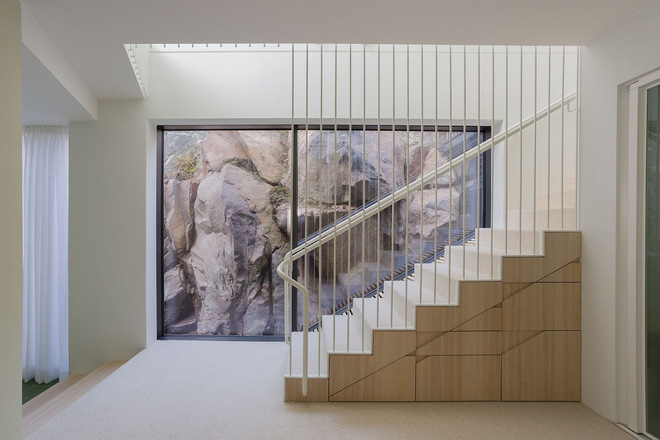 Bức tường kính nơi chân cầu thang dẫn lên tầng 2 với những mõm đá khổng lồ trông hệt như một bức tranh lớn.