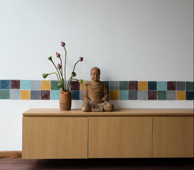 Đối diện góc tiếp khách là hệ tủ kệ được gắn cố định vào tường tạo thể tích lưu trữ tha hồ cho gia chủ. Bên trên còn đặt bức tượng phật cộng bình hoa sen như một góc linh thiêng trong nhà.