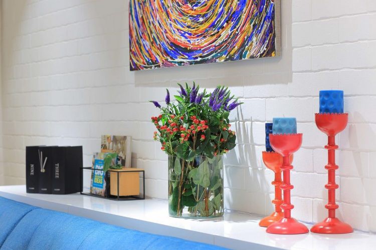 Không gian nơi tiếp khách được bài trí đơn giản với kệ sách báo nhỏ, nến thơm và lọ hoa.