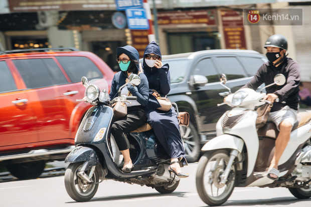 Ảnh: Nhiệt độ ngoài đường tại Hà Nội lên tới 50 độ C, người dân trùm khăn áo kín mít di chuyển trên phố - Ảnh 1.