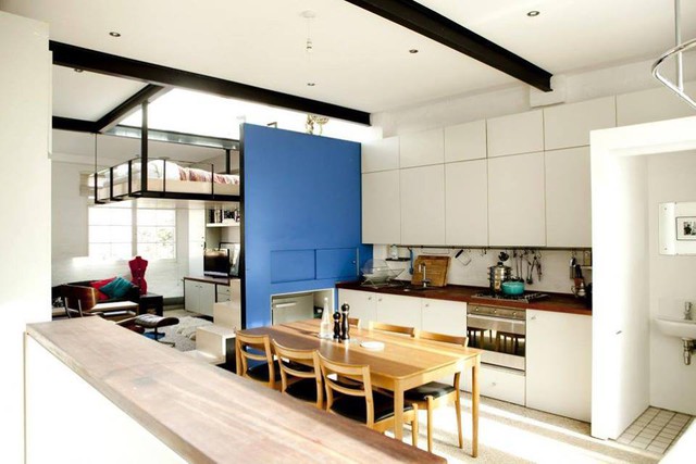 Tấm vách ngăn một mặt màu xanh và một mặt màu đen là bức tường duy nhất trong ngôi nhà giúp phân chia không gian giữa khu vực bếp ăn và phòng khách. 