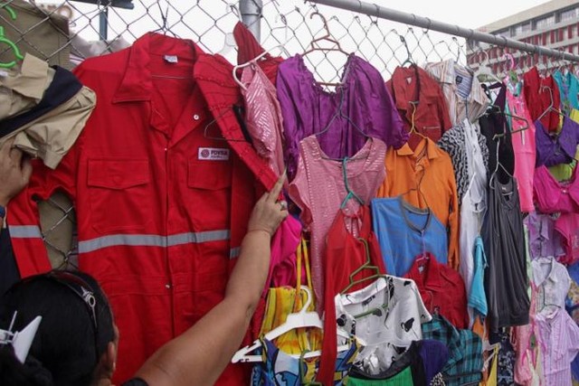 
Đồng phục PDVSA được bày bán cùng các loại quần áo khác ở chợ tại thành phố Maracaibo, Venezuela - Ảnh: Reuters
