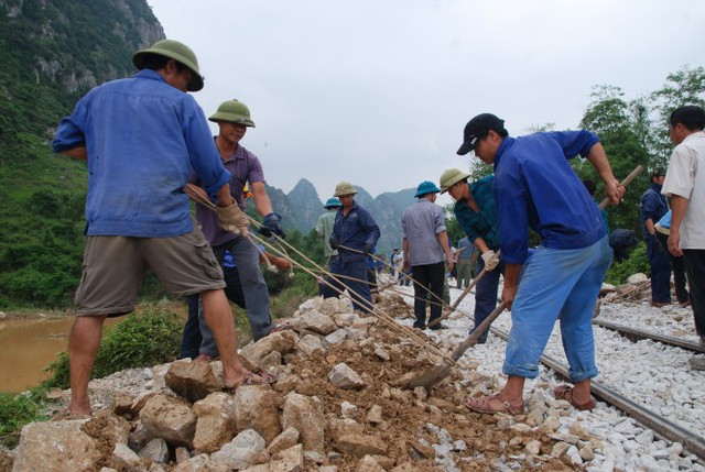 Công nhân đường sắt san mặt bằng hai bên taluy đường để tàu chạy qua an toàn - Ảnh: QUỐC NAM