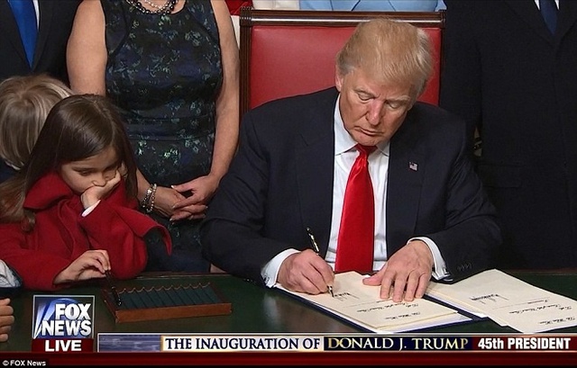 Arabella, 5 tuổi, cháu ngoại Trump, con gái lớn của Ivanka và Jared xuất hiện trong bộ trang phục màu đỏ rực rỡ trong khi mải nghịch bút lúc ông ký văn bản.