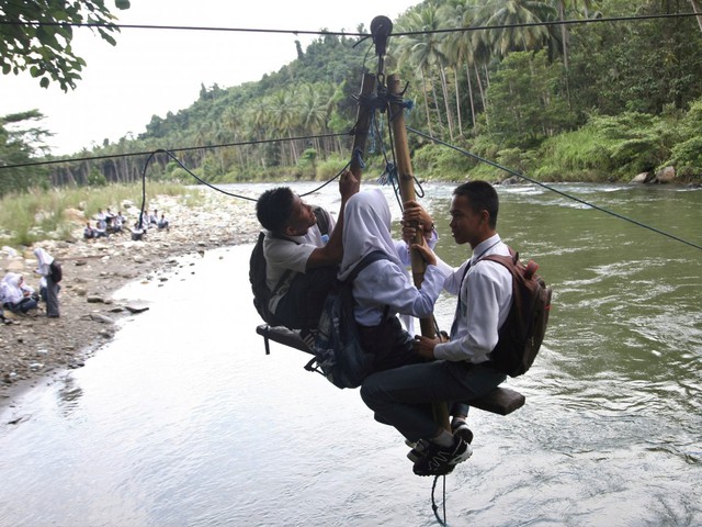 
Học sinh đu mình trên những chiếc cáp treo tự chế để tới lớp ở Kolaka Utara, Indonesia.

