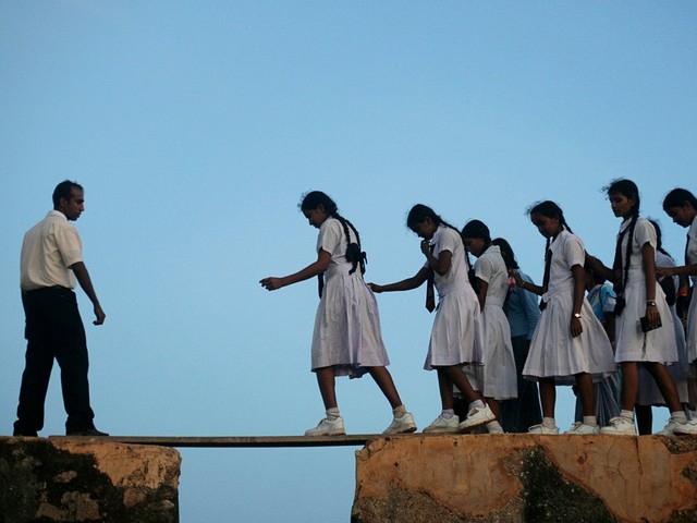 
Những nữ sinh Sri Lanka phải bước qua tấm ván gỗ, nối giữa hai phần của bức tường cổ được xây dựng từ thế kỷ 16, để tới lớp.
