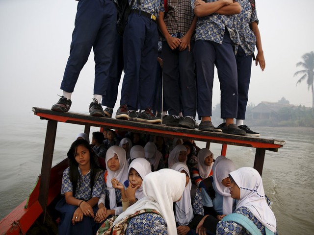 
Những chiếc thuyền gỗ chòng chành như sắp chìm cũng được dùng dể đưa học sinh tới lớp tại Indonesia.
