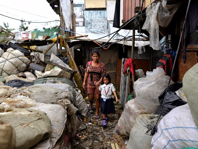 
Trong ảnh là cô Weng Ruda, 36 tuổi, sinh sống tại một khu ổ chuột ở Manila đang dắt con gái đi học.

