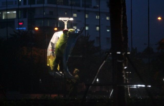 
Hai người đàn ông đang nỗ lực treo lên một tấm áp phích trong mưa to, gió lớn vì ảnh hưởng của bão số 12 tại Trung tâm Báo chí phục vụ APEC ở thành phố Đà Nẵng. Công việc tưởng như đơn giản lại gặp rất nhiều thách thức trong điều kiện thời tiết xấu.

