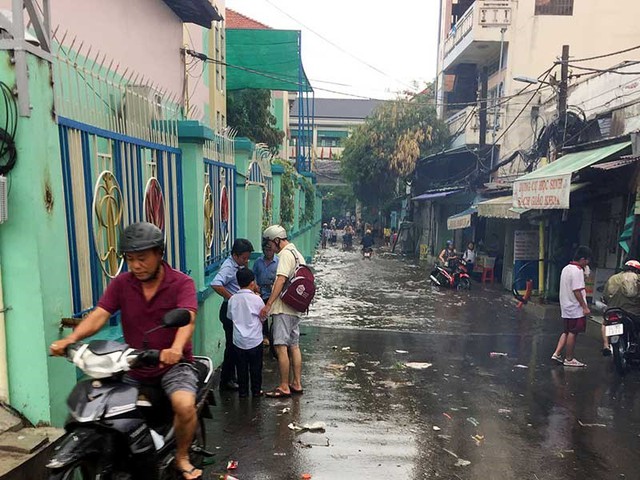Hẻm 687 đường Kinh Dương Vương có hai trường học bị ngập khiến việc đưa đón con của phụ huynh gặp nhiều khó khăn. Ảnh: L.THOA