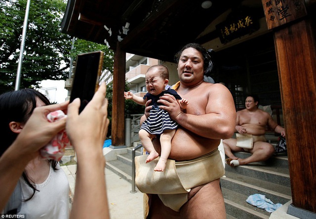 
Võ sĩ sumo Kyokutaisei chụp hình cùng một em bé trước cửa đền.
