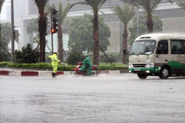 
Một chiến sỹ cảnh sát giao thông đội mưa làm nhiệm vụ trên đường Phạm Hùng.

