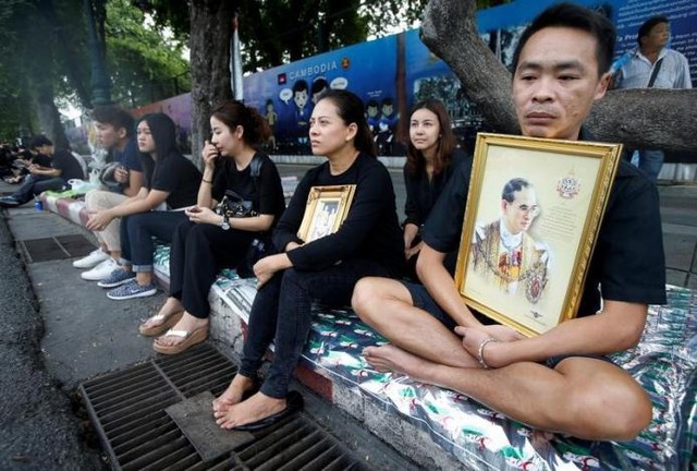
Bên ngoài các con đường, người dân Thái Lan trong trang phục màu đen, tay ôm di ảnh của Vua với dòng nước mắt nghẹn ngào.
