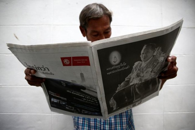 
Người đàn ông đọc báo về tin tức Vua Bhumibol băng hà.
