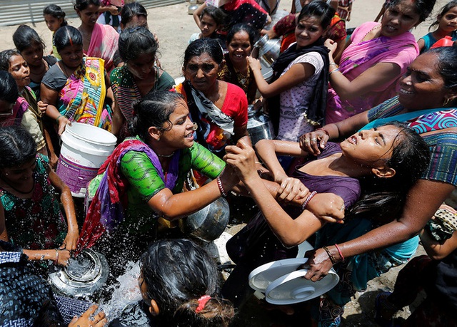 
Những người phụ nữ tranh nhau nước uống thu thập từ một tàu chở dầu thành phố vào một ngày mùa hè nóng ở ngoại ô thành phố Ahmedabad, Ấn Độ.

