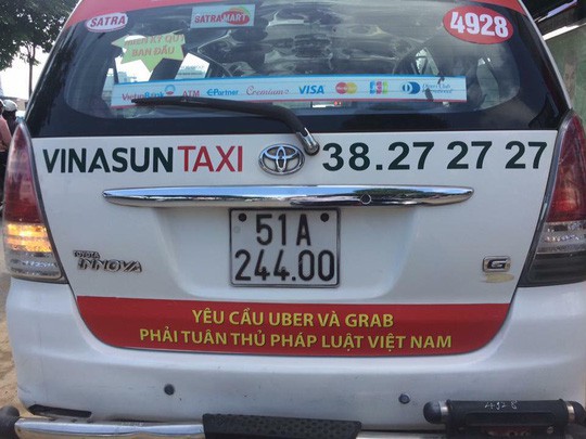 
Khẩu hiệu phản đối Uber, Grab dán sau một taxi Vinasun lưu thông trên đường phố TP HCM sáng 8-10.
