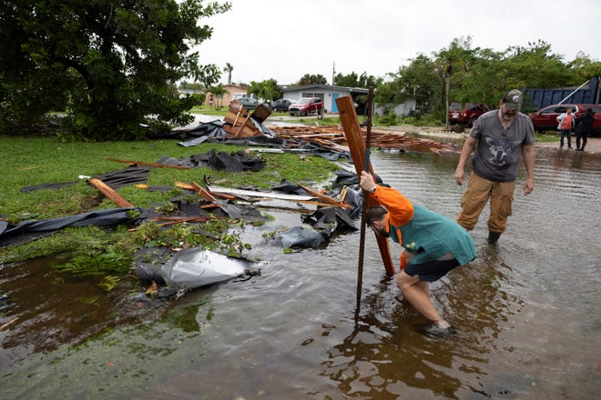 People remove debris from a street after a tornado hit the area as Hurricane Milton approaches Fort Myers, Florida.