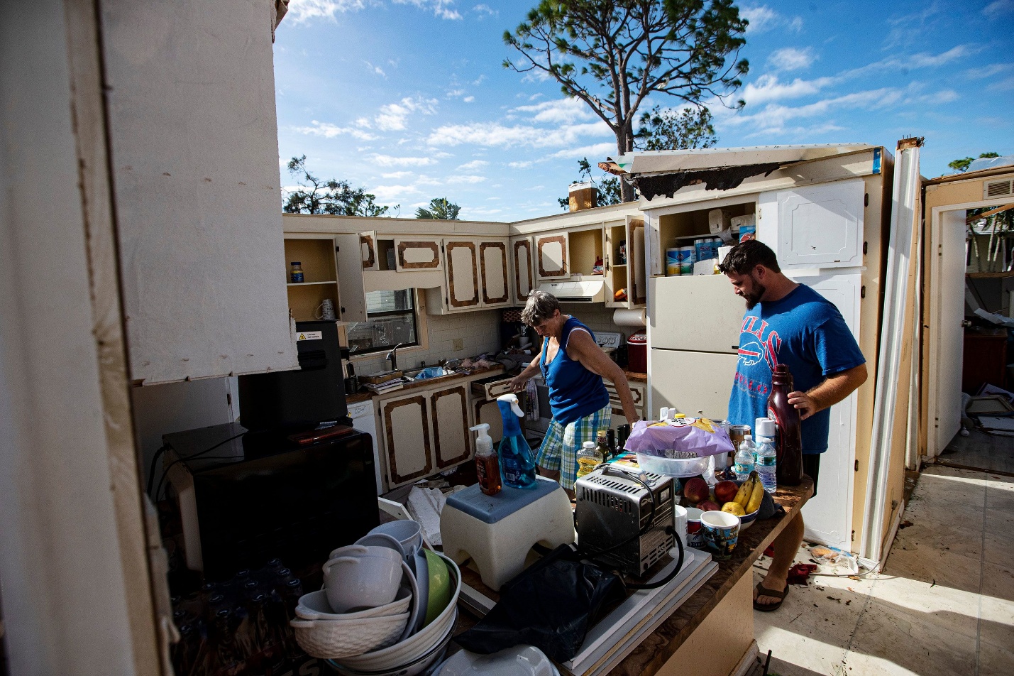 Liz Kelly and her son Matt salvage items from their destroyed home in North Fort Myers, Florida, on Thursday. A tornado associated with Hurricane Milton ripped through their neighborhood. Matt dove on top of his mother as the roof was peeling off the home. She says he saved her life.