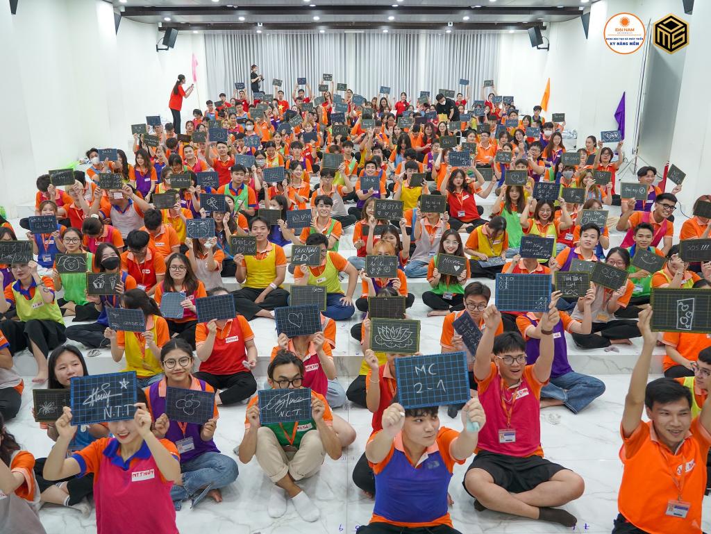 A group of people sitting on the floor holding signs  Description automatically generated