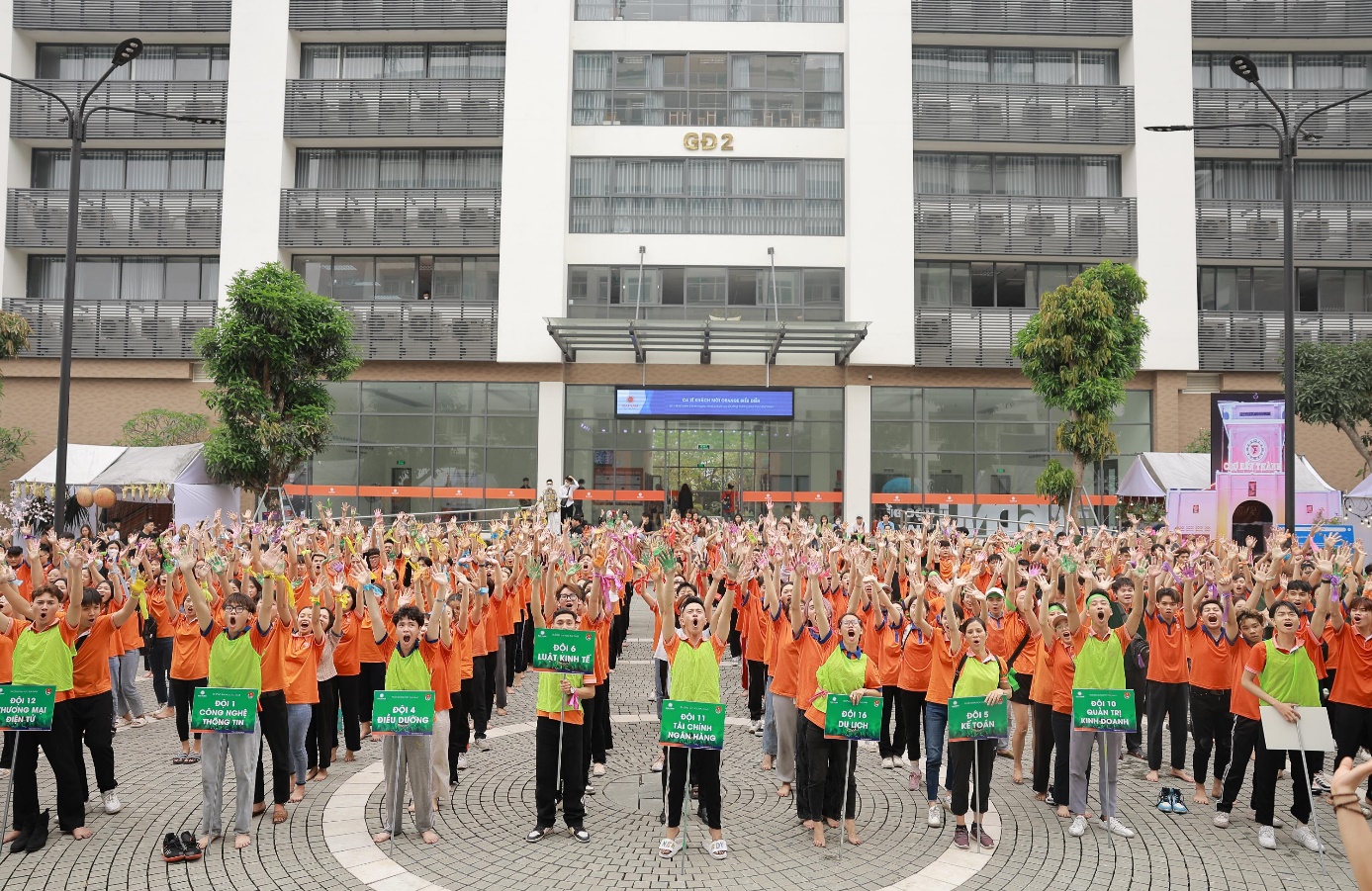 A group of people in orange shirts holding signs  Description automatically generated