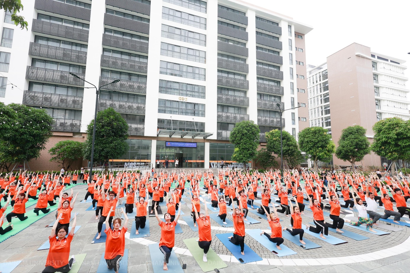 A group of people in orange shirts doing yoga  Description automatically generated