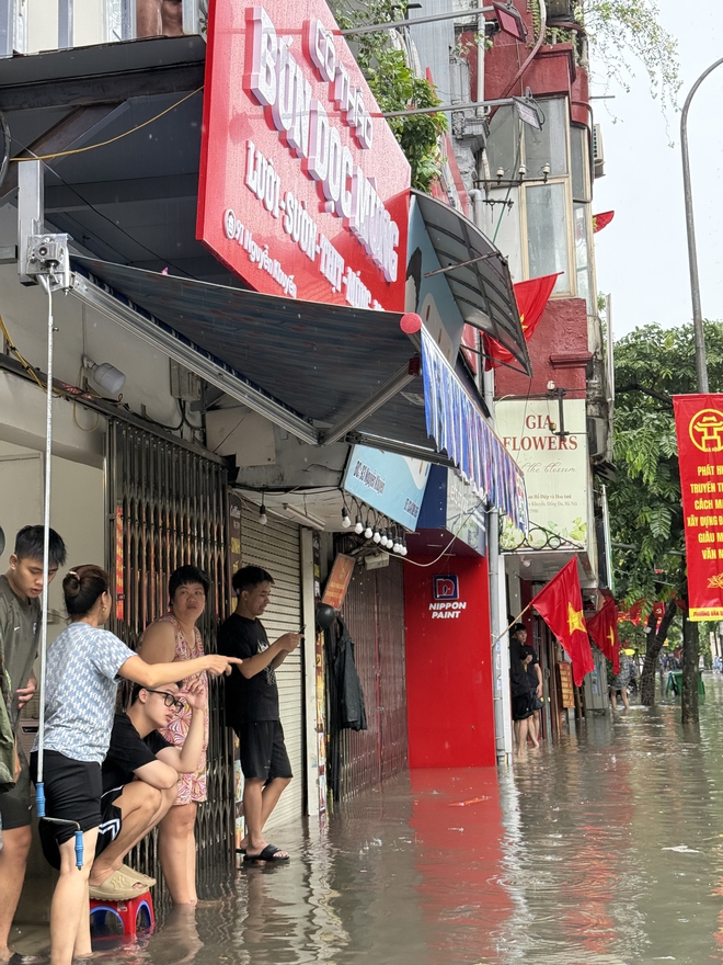 Loạt hàng quán ngập nước vẫn mở cửa, trở thành chỗ trú cho khách giữa thời tiết mưa lớn ở Hà Nội- Ảnh 8.