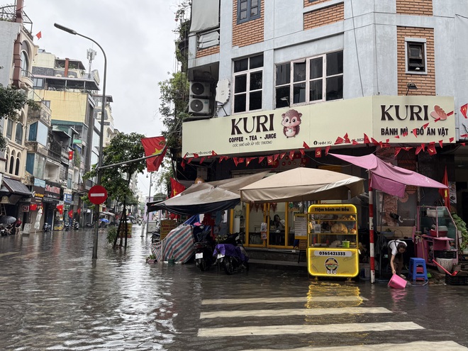 Loạt hàng quán ngập nước vẫn mở cửa, trở thành chỗ trú cho khách giữa thời tiết mưa lớn ở Hà Nội- Ảnh 1.
