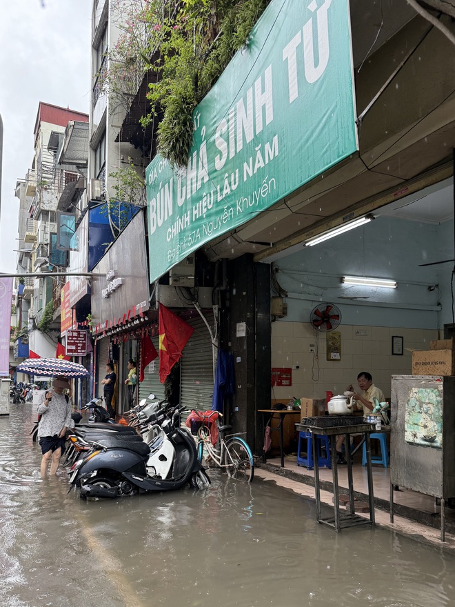 Loạt hàng quán ngập nước vẫn mở cửa, trở thành chỗ trú cho khách giữa thời tiết mưa lớn ở Hà Nội- Ảnh 2.