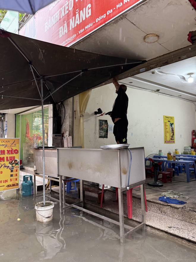 Loạt hàng quán ngập nước vẫn mở cửa, trở thành chỗ trú cho khách giữa thời tiết mưa lớn ở Hà Nội- Ảnh 10.