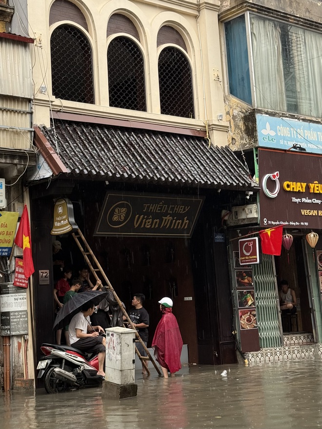 Loạt hàng quán ngập nước vẫn mở cửa, trở thành chỗ trú cho khách giữa thời tiết mưa lớn ở Hà Nội- Ảnh 11.