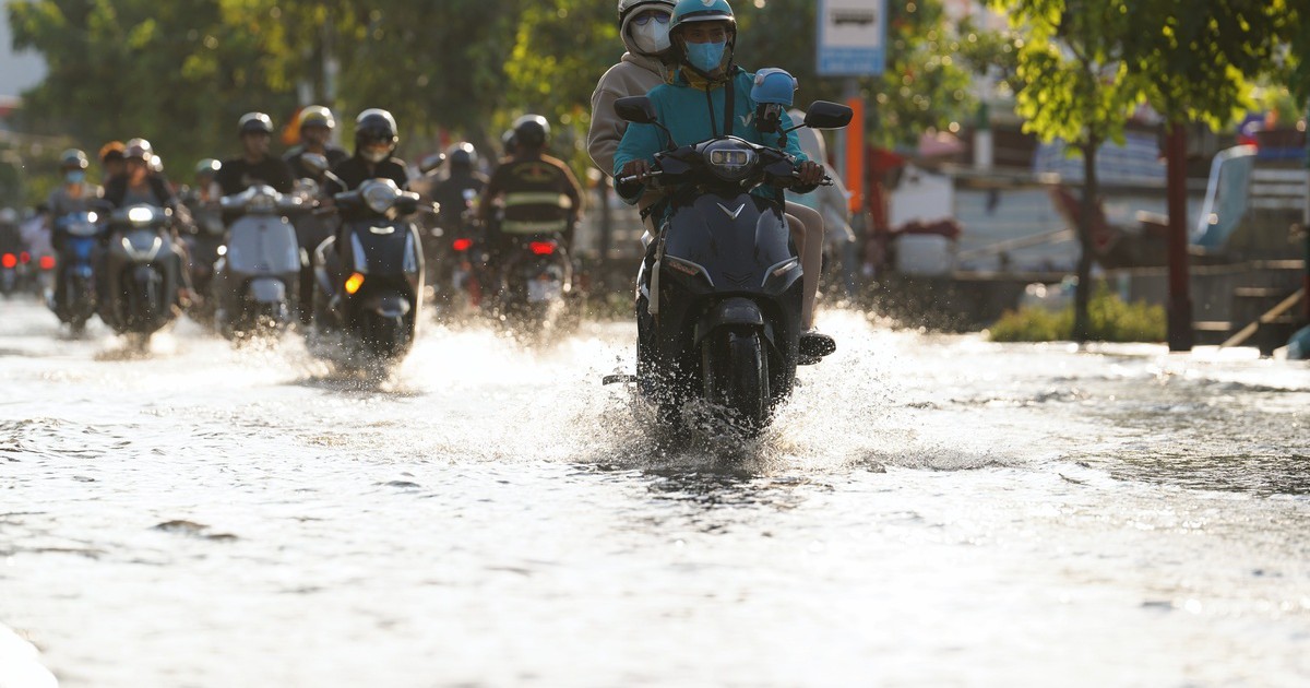 Triều cường dâng cao giữa trời nắng nóng, người dân TP.HCM bì bõm lội nước đi về
