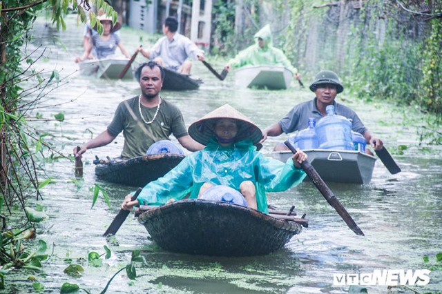Dân vùng rốn lũ Hà Nội tấp nập chèo thuyền đi lấy nước miễn phí - Ảnh 1.