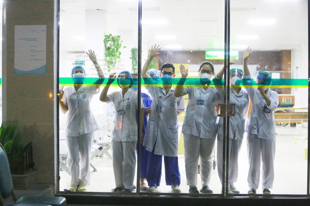 Hình ảnh các y bác sĩ tại Bệnh viện Bạch Mai vẫy tay chào qua cửa kính: Họ đang ngày đêm chiến đấu ở tuyến đầu nhưng vẫn luôn lạc quan như vậy - Ảnh 1.