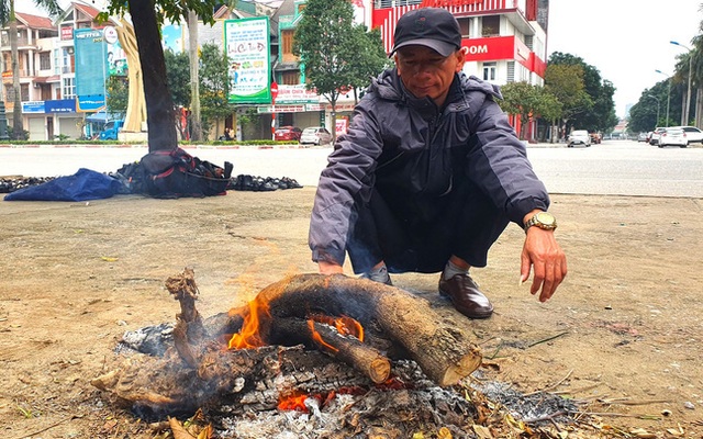 Anh Minh - người bán giày dép rong trên đường TP. Vinh (Nghệ An) mấy hôm nay phải vơ củi khô nhóm bếp để sưởi ấm ngay trên hè phố.