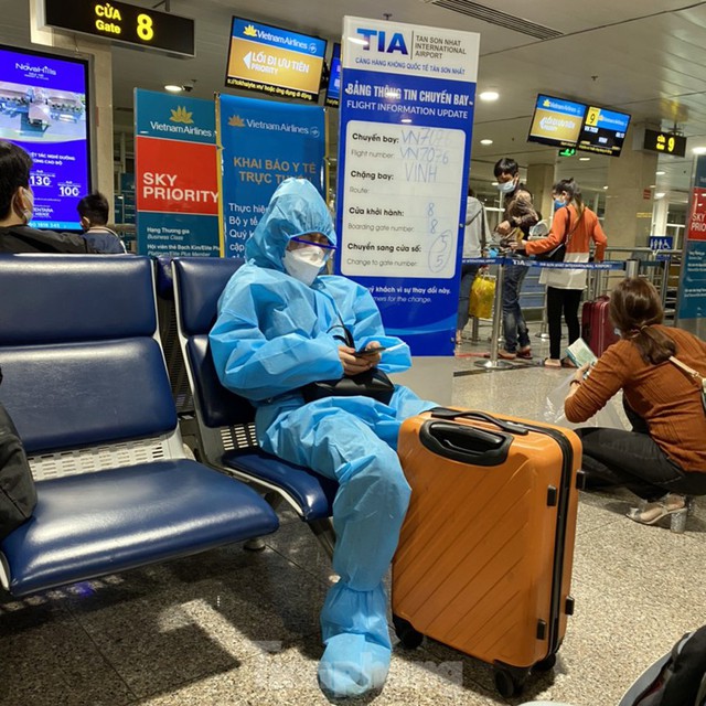 Hành khách mặc áo mưa, bảo hộ kín mít khi đi máy bay tại Tân Sơn Nhất - Ảnh 4.