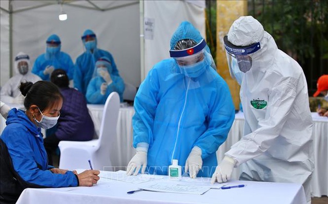 Nhân viên y tế hướng dẫn người dân khai vào tờ khai khi đến test nhanh COVID-19 ở Hà Nội. Ảnh: Minh Quyết/TTXVN.