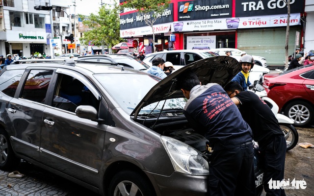 Kỹ thuật viên một ga ra kiểm tra ô tô bị ngập nước ngay tại hiện trường trên đường Lê Duẩn, quận Hải Châu, Đà Nẵng - Ảnh: TẤN LỰC