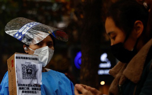 Nhân viên mặc đồ bảo hộ hướng dẫn người dân quét mã sức khỏe QR tại một địa điểm xét nghiệm PCR ở Bắc Kinh, Trung Quốc ngày 11-11 - Ảnh: REUTERS