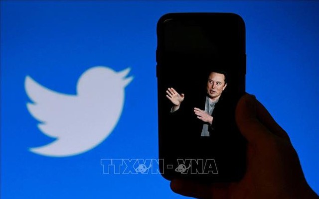 Tỷ phú Elon Musk trên màn hình điện thoại và biểu tượng Twitter (phía sau). Ảnh: AFP/TTXVN